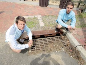 Tyler Lubin, left, and Noah Tucker at a storm drain at the Navesink River in Fair Haven. The debris buildup on at the drain shows what can flow into the river.