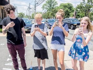 Four siblings of the Conery family, from left: Shane, 18, Mikey, 13, Kayla, 14 and Sarah, 20, of Middletown, playing Pokemon GO on the streets of Red Bank. "I like catching 'em all," Sarah said.