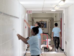 Goldman Sachs employees give the Red Bank Primary School halls a fresh coat of paint last Saturday in anticipation of the new school year.