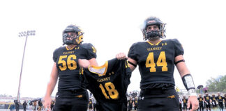 Saint John Vianney’s Zach Scully, left, and Christian Buchanan stood with Aaron Van Trease’s jersey during the coin toss in the Lancers game against Marlboro.