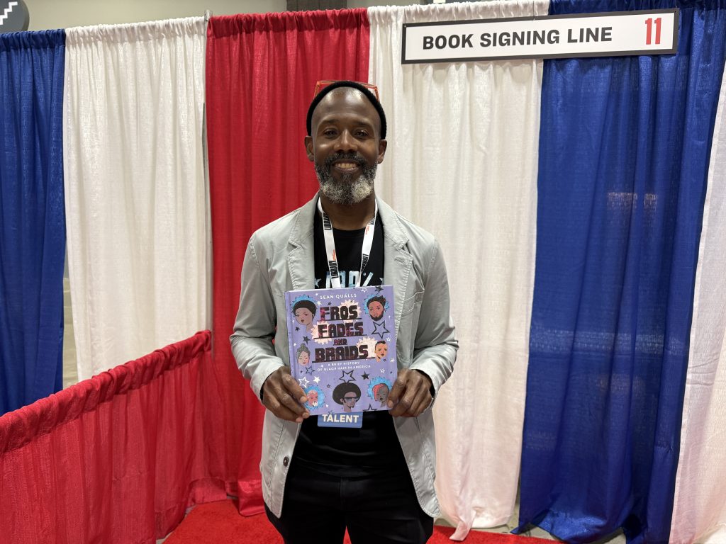 Author Sean Qualls holding his book at the National Book Festival